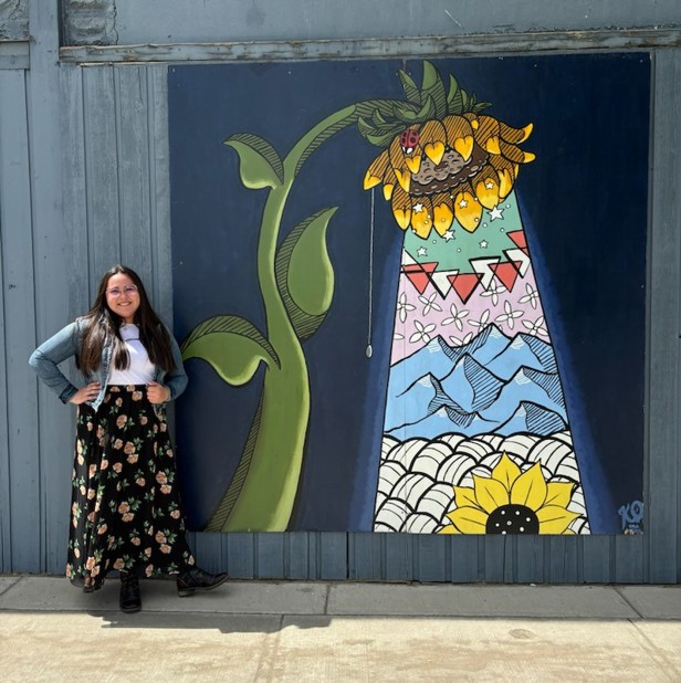 Artist stands beside her painting