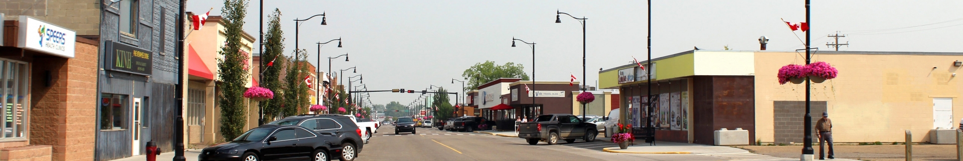 Cars parked and driving down the Main Street of the Town of Olds